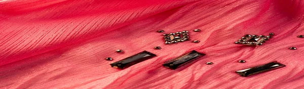 İpek desenli, kırmızı kumaş ve dekoratif yüzlü taşlar. parlak renkli taşlarla dokuma arkaplanı, doku arkaplan tasarımı