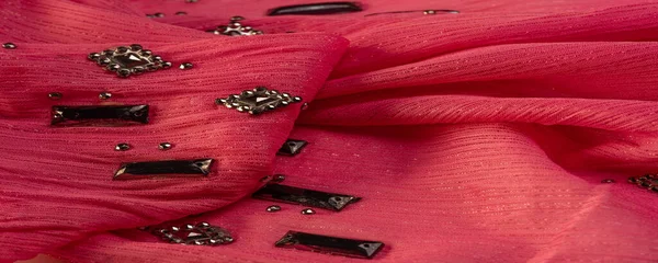 İpek desenli, kırmızı kumaş ve dekoratif yüzlü taşlar. parlak renkli taşlarla dokuma arkaplanı, doku arkaplan tasarımı