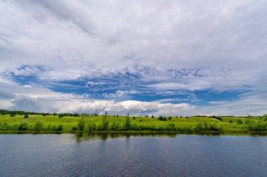 Nehir manzarası, yeşillik ve bulutlu gökyüzü