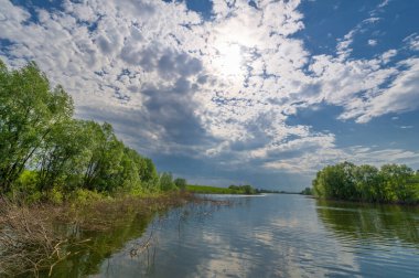 Nehir manzarası, yeşillik ve bulutlu gökyüzü