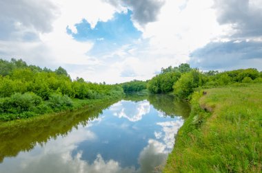 Nehir manzarası, yeşillik ve bulutlu gökyüzü