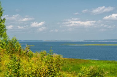 Nehir manzarası, yeşillik ve bulutlu gökyüzü