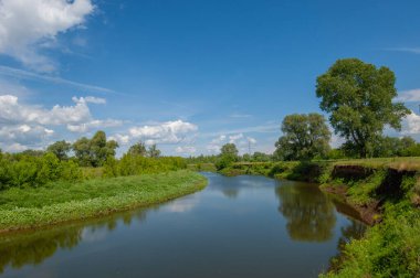 Nehir manzarası, yeşillik ve bulutlu gökyüzü