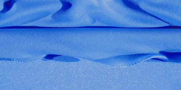 blue silk. Smooth elegant blue luxury silk fabric can be used as an abstract background with copy space, close-up. colorful texture