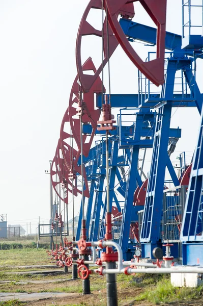 石油和天然气工业 石油泵杰克在石油领域的工作 白色的云 蓝蓝的天空 油井泵 石油和天然气工业 石油泵杰克在石油领域的工作 — 图库照片