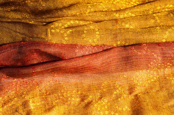 The texture of wool fabric yellow red golden. Women\'s scarf, the perfect backdrop.  cravat, neckerchief, kerchief, muffler, throw. a length or square of fabric worn around the neck or head.