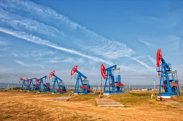 Petrol ve gaz endüstrisi. yağ pompası jack petrol sahası üzerinde çalışır. beyaz bulutlar ve mavi gökyüzü. Petrol pompası. Petrol ve gaz endüstrisi. yağ pompası jack petrol sahasındaki çalışmaları.