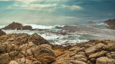 Güzel deniz manzarası, kayalık kıyı şeridi, ufukta güneş ışığı. Doğanın bileşimi. Günbatımı manzara arka planı. Bulutlu gökyüzü. Suyun yansıması. Kaliforniya kıyısı. Uzun bir atış.
