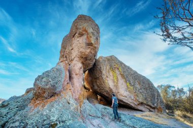 San Benito County ve Monterey County, Kaliforniya, ABD - 10 Ekim 2020, Pinnacles Ulusal Parkı 'nda büyük bir kayanın yanında bir turist. Kavram, doğada aktif eğlence, turizm.