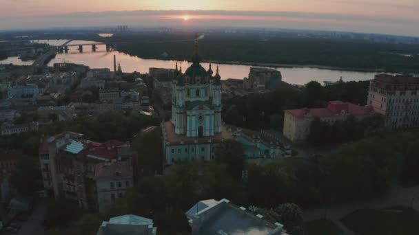 Vista aérea de la iglesia de St. Andrews al amanecer, centro histórico, distrito de Podolsk, Kiev, Ucrania. Un dron con una cámara vuela desde la Iglesia de San Andrés. Vuele alrededor de la iglesia de St. Andrews en Kiev. — Vídeos de Stock