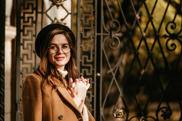 beautiful young woman in beret and coat walks in the autumn city