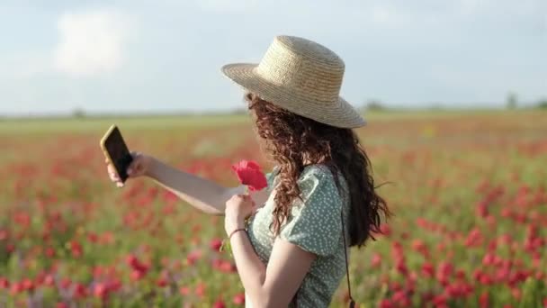Portrét mladé krásné kudrnaté brunetky žena v klobouku dělat selfie v makové pole 