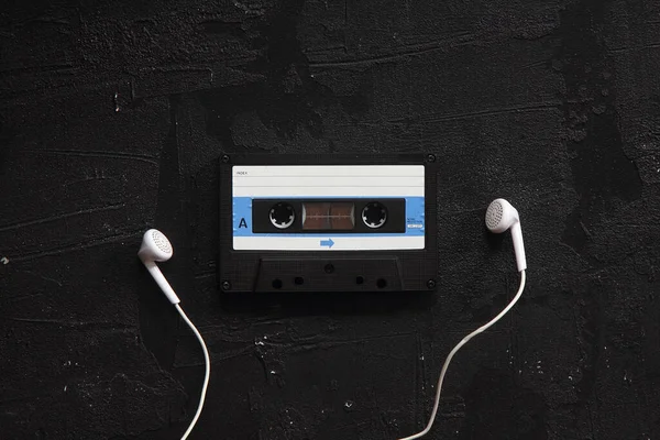 Mavi-beyaz ses kaseti ve beyaz arka planda kulaklıkları olan bir kaset. Parti 90 'ların konsepti