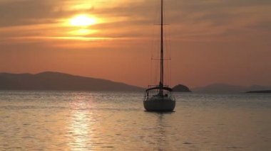 Günbatımında yalnız yelkenli. Turuncu güneşli atmosferik deniz manzarası.