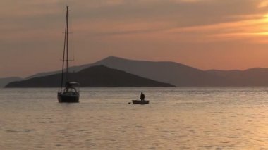 Günbatımında yalnız yelkenli. Turuncu güneşli atmosferik deniz manzarası.