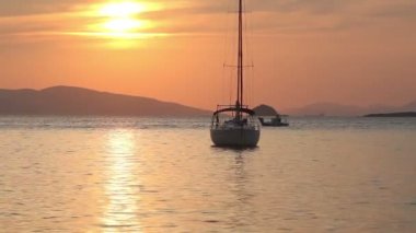 Günbatımında yalnız yelkenli. Turuncu güneşli atmosferik deniz manzarası.