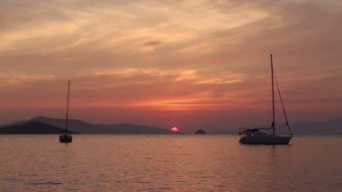 Günbatımında yalnız yelkenli. Turuncu güneşli atmosferik deniz manzarası.