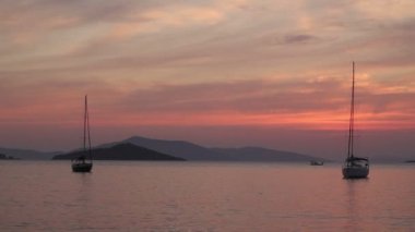 Günbatımında yalnız yelkenli. Turuncu güneşli atmosferik deniz manzarası.