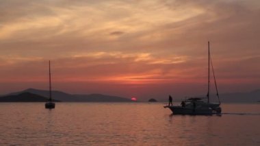 Günbatımında yalnız yelkenli. Turuncu güneşli atmosferik deniz manzarası.