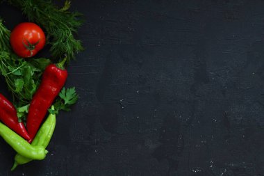 Yemek pişirme arka planı siyah taş masada. Taze sebzeler, bitkiler. Yemek yapmak için gerekli malzemeler. Kopyalama alanı olan üst görünüm.