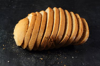 Siyah arka planda dilimlenmiş beyaz ekmek somunu.