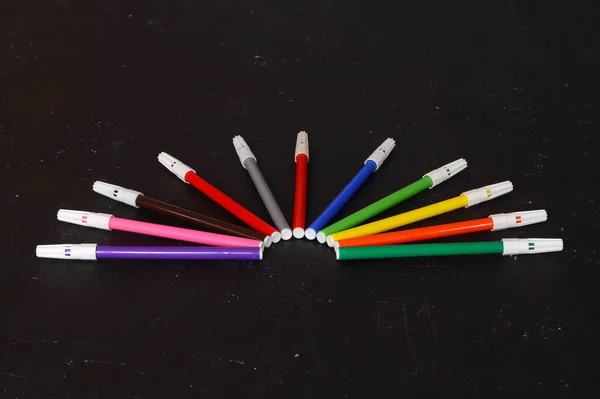 Multi-colored markers for drawing. Markers on a black isolated background