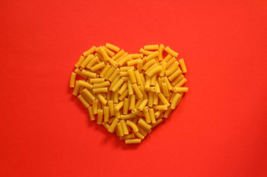 Kırmızı arka planda kalp şeklinde makarna..