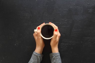 Kırsal ahşap masa zemininde kahve bardaklarını tutan kadın eller, bir kadının elleri, bir fincan sert kahveyi ahşap masada tutuyor. Fotokopi alanı olan kahve fanı üst görünümü.