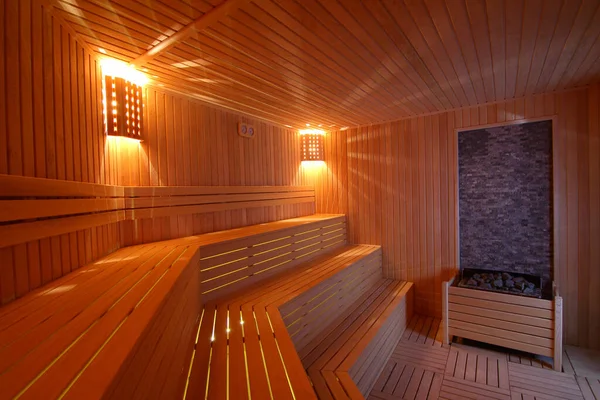 Sauna odasında otur. Taş ısıtıcılı boş ahşap buhar odası. Sağlıklı olmak için sauna odası. Sauna odası ve geleneksel sauna aksesuarları. Sağlıklı ve spa tarzı..