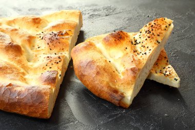 Slices of Ramadan Pita (Ramazan Pidesi) Traditional Turkish bread for holy month Ramadan on black background. Ramadan concept.