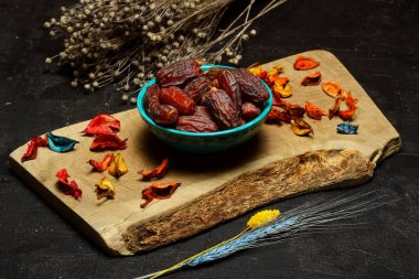 Gümüş kaplarda, ahşap bir masada kurumuş hurmalar. Kurumuş hurma kompozisyonu ahşap masadaki ramazan kabında.