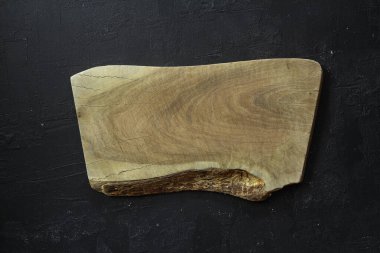 Boş ahşap kesme tahtası siyah taştan bir arka planda yatıyordu. Üst görünüm