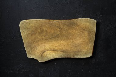 Boş ahşap kesme tahtası siyah taştan bir arka planda yatıyordu. Üst görünüm