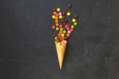 Siyah arka planda renkli şekerli dondurma külahının en üst görüntüsü