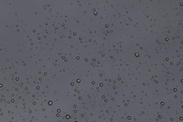 Rain drops on the glass in the spring afternoon. Close up of a window with rain drops falling down.The rain drops on household windows. Focus on rain drops. concept of sadness, frustration