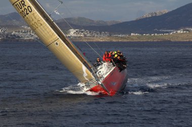 Bodrum, Türkiye. 10 Aralık 2017: Ünlü tatil beldesi Bodrum 'un kıyılarında, Ege Denizi' nin mavi sularında rüzgarlı havada yelken açan yelkenliler.