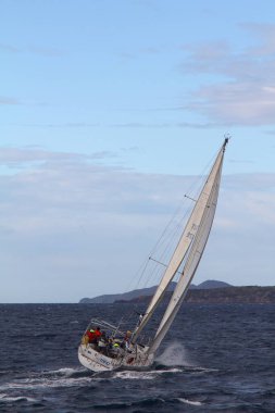 Bodrum, Türkiye. 10 Aralık 2017: Ünlü tatil beldesi Bodrum 'un kıyılarında, Ege Denizi' nin mavi sularında rüzgarlı havada yelken açan yelkenliler.