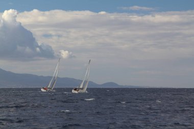 Bodrum, Türkiye. 10 Aralık 2017: Ünlü tatil beldesi Bodrum 'un kıyılarında, Ege Denizi' nin mavi sularında rüzgarlı havada yelken açan yelkenliler.