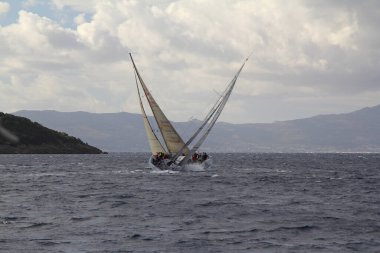Bodrum, Türkiye. 10 Aralık 2017: Ünlü tatil beldesi Bodrum 'un kıyılarında, Ege Denizi' nin mavi sularında rüzgarlı havada yelken açan yelkenliler.