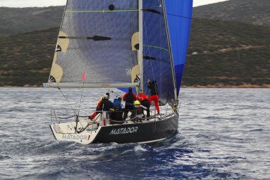 Bodrum, Türkiye. 10 Aralık 2017: Ünlü tatil beldesi Bodrum 'un kıyılarında, Ege Denizi' nin mavi sularında rüzgarlı havada yelken açan yelkenliler.