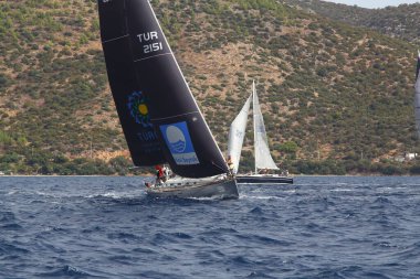Bodrum, Türkiye. 17 Ekim 2020: Bodrum 'un ünlü tatil beldesi Bodrum' un kıyılarında, Ege Denizi 'nin mavi sularında rüzgarlı havada yelken açan yelkenliler.