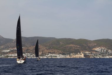 Bodrum, Türkiye. 17 Ekim 2020: Bodrum 'un ünlü tatil beldesi Bodrum' un kıyılarında, Ege Denizi 'nin mavi sularında rüzgarlı havada yelken açan yelkenliler.