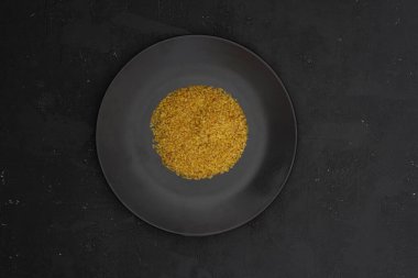 Siyah arka planda siyah bir tabakta bulgur buğdayı. Üst görünüm, boşluğu kopyala. Düz yatıyordu.