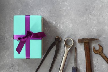 Babalar Günü 'nün arka planında bir hediye, ahşap bir arka planda bir kartpostal, tamir aletleri ve bir hediye kutusu.