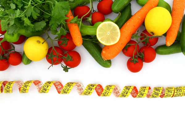 Ölçüm bandıyla diyet kavramı. Beyaz arka planda taze sebzeler. Domates, yeşil biber, havuç, limon, salatalık, maydanoz ve sarı mezura.,