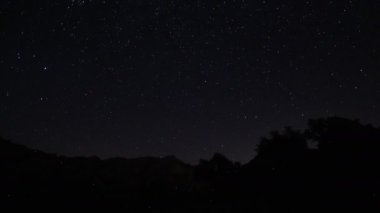 Gece gökyüzünde hareket eden yıldızların zaman çizelgesi. Önünde bir dağ tepesi olan Samanyolu 'nun yıldızlarının görüntüsü. Gece gökyüzü doğa yaz manzarası. Perseid Meteor Yağışı gözlemi.
