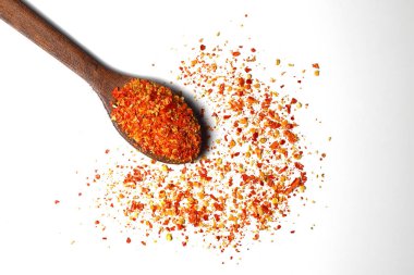 Kırmızı biber tozu ya da beyaz arka planda izole edilmiş ahşap kaşıkla kuru kırmızı biber.