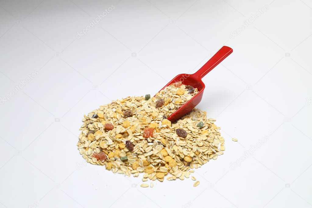 Oat flakes in Red spoon isolated on White background. Heap of oats for package of oatmeal or granola
