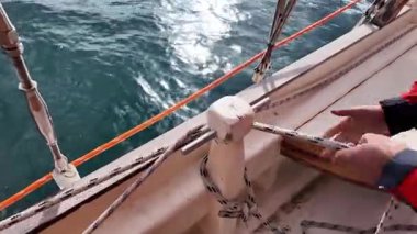 Deniz hayatı. Bir adam hızla ipi sıkılaştırır ve yelken açmak için güvenli bir şekilde bağlar..