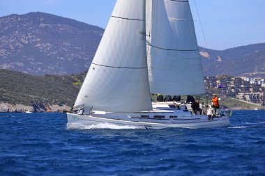 Bodrum, Hindi. 16 Mart 2024: Yelkenliler Ege Denizi 'nin mavi sularında, ünlü tatil beldesi Bodrum' un kıyılarında rüzgarlı havada yelken açıyorlar..